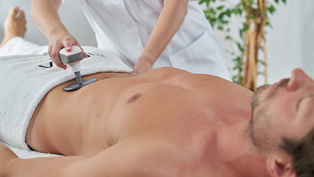 Homme reçois un traitement de remodelage du corps à l'aide du matériel médical INDIBA® Deep Beauty